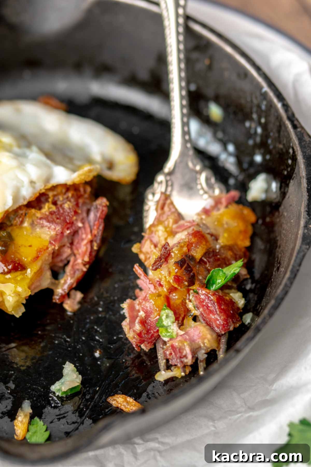 A fork with a bite of corned beef fritter on it.