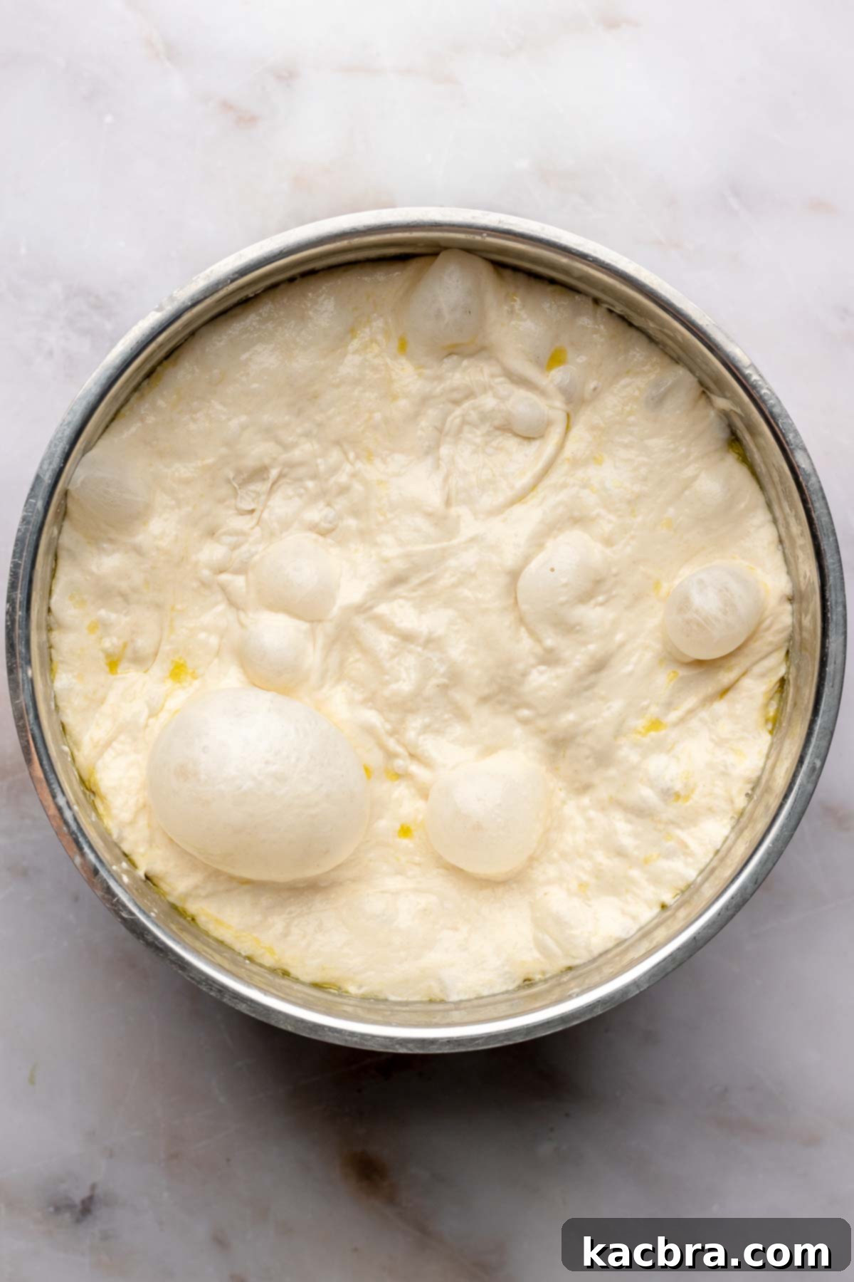 Aromatic Pesto Focaccia 11 Risen, bubbly focaccia dough in a bowl.