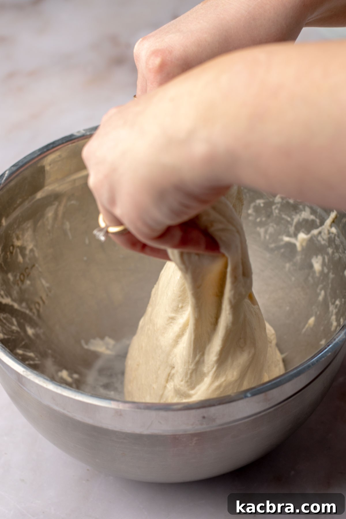 Aromatic Pesto Focaccia 7 Hands lift bread dough upwards.
