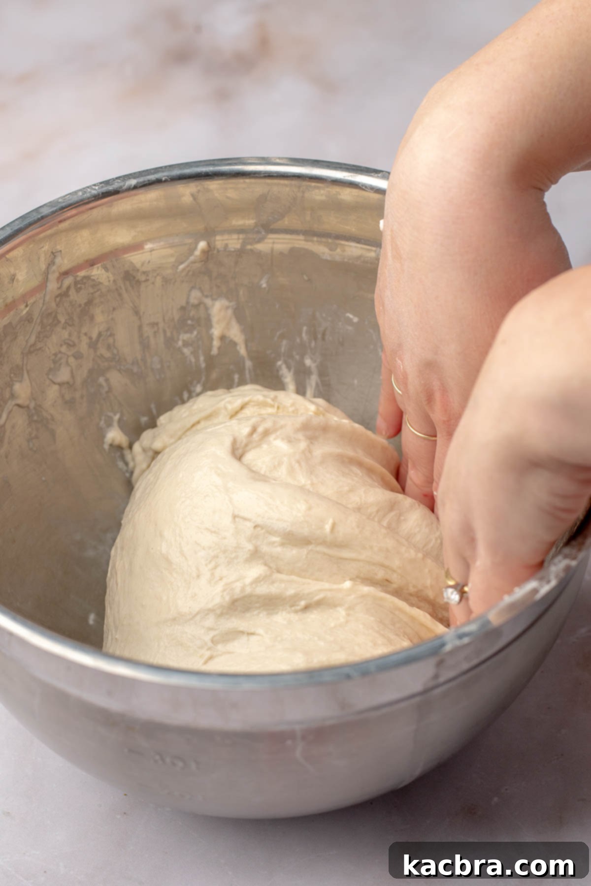 Aromatic Pesto Focaccia 8 Hands fold bread dough on top of itself in a bowl.