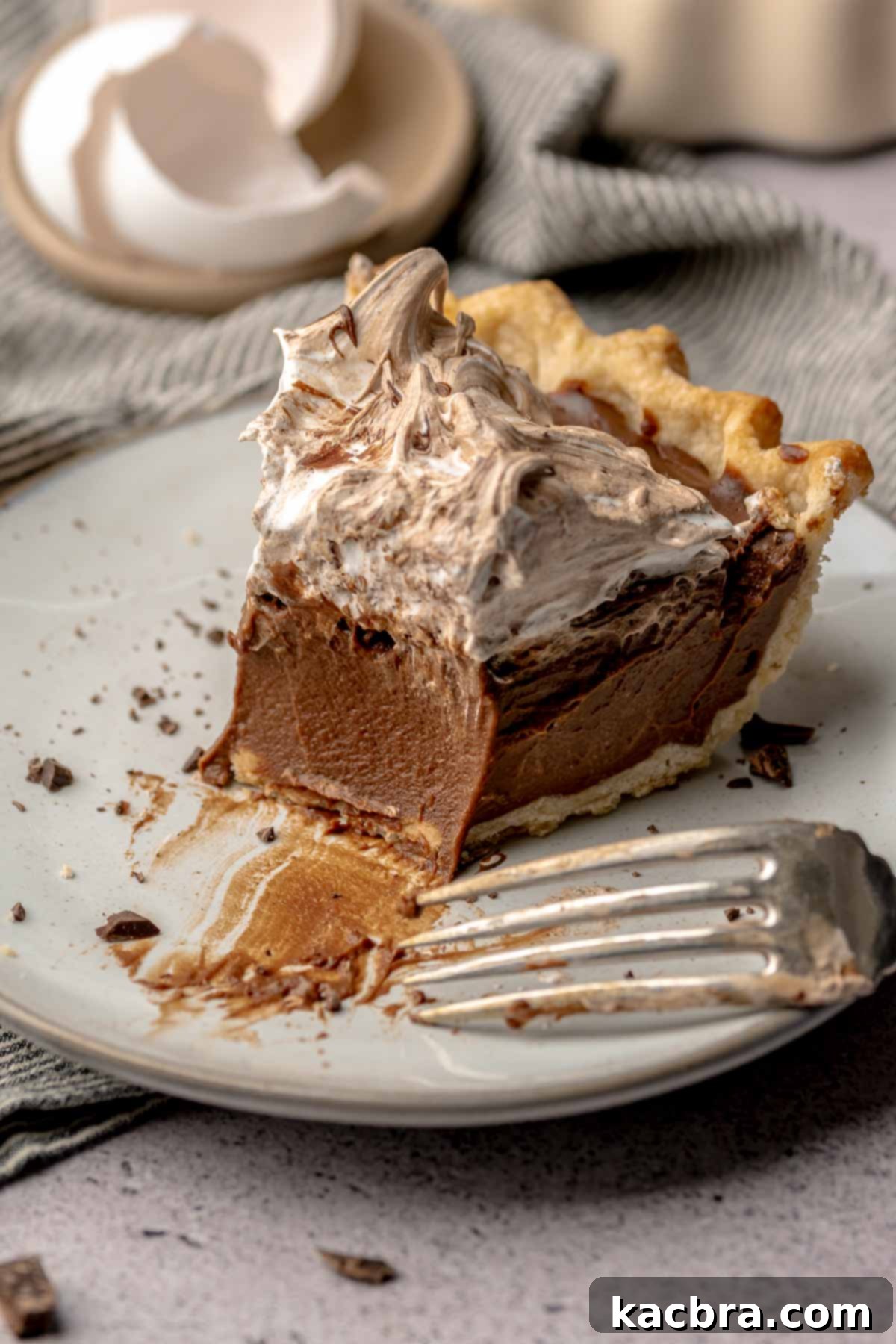 Chocolate meringue pie on a plate with a bite removed.