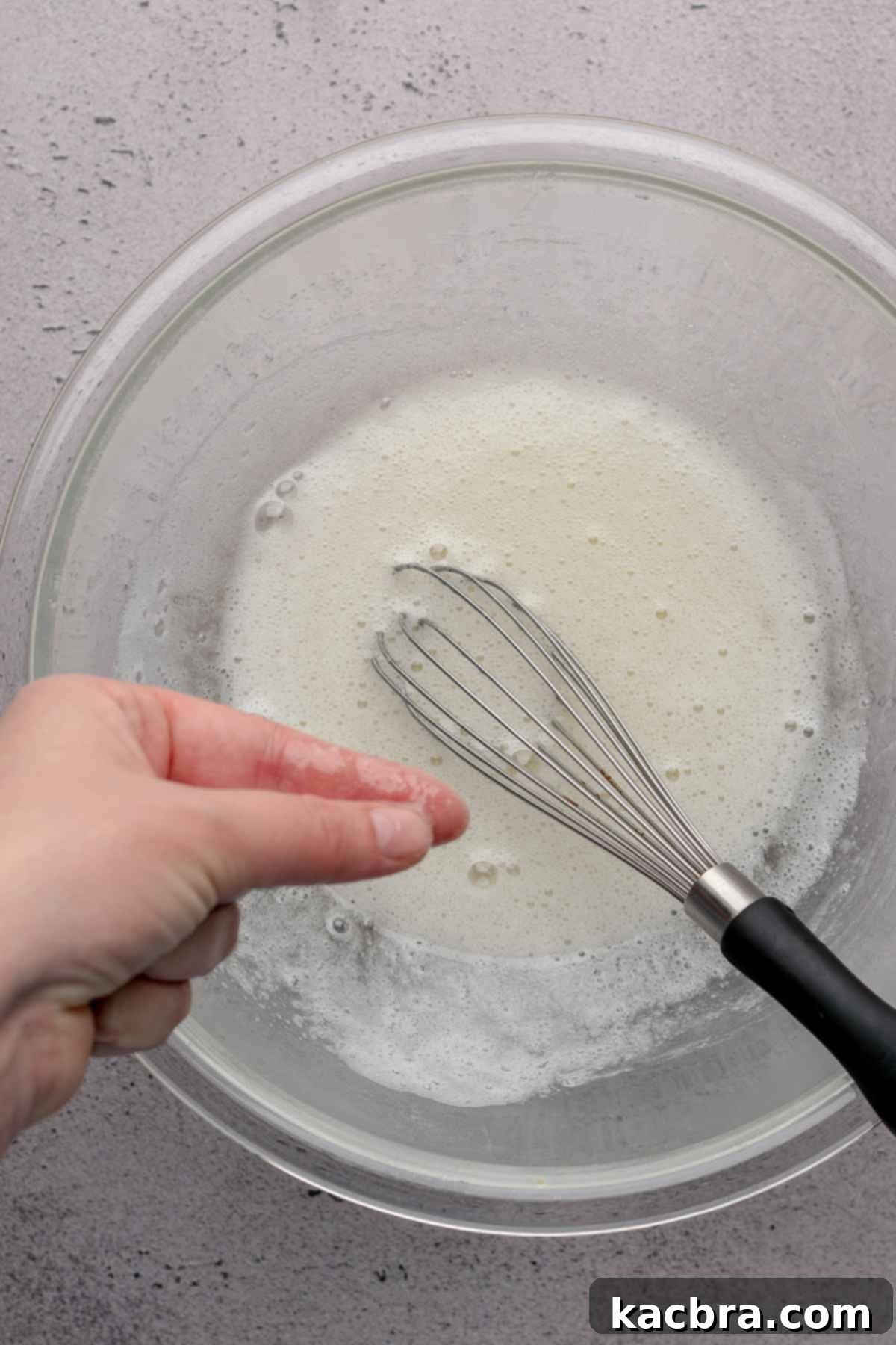 Fingers feel hot meringue in a bowl.