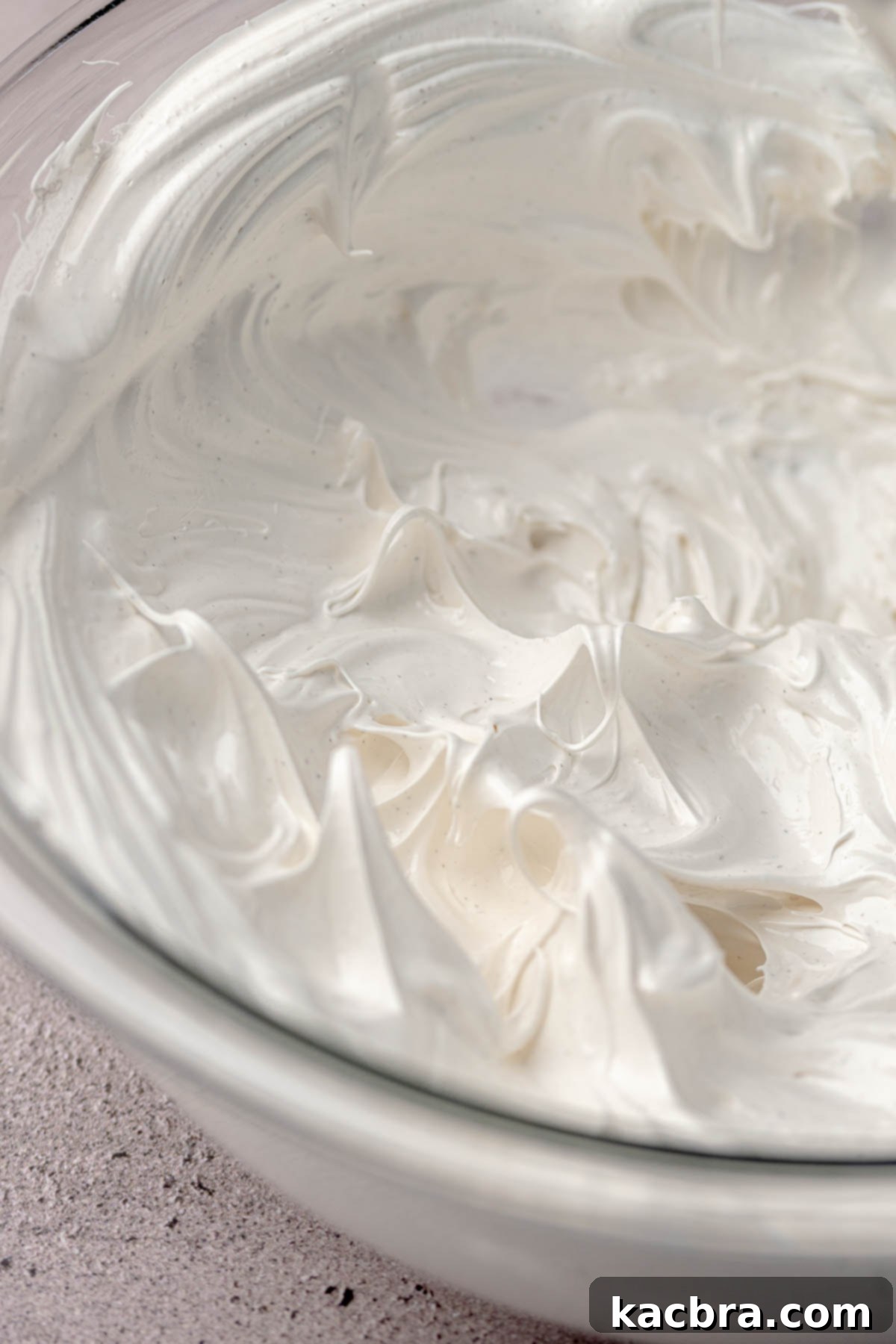 Fluffy, stiff-peaked whipped meringue in a mixing bowl.