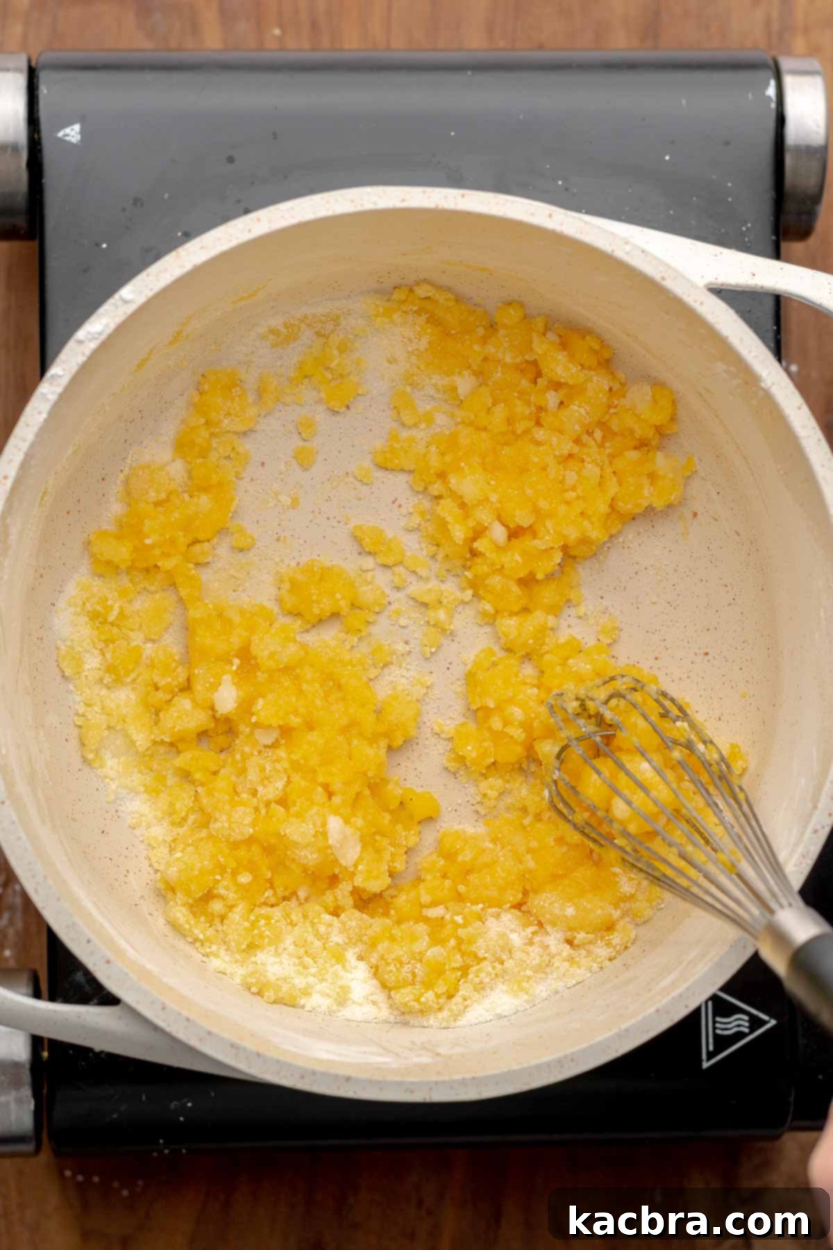 Egg yolks, sugar, and cornstarch being whisked together in a saucepan.