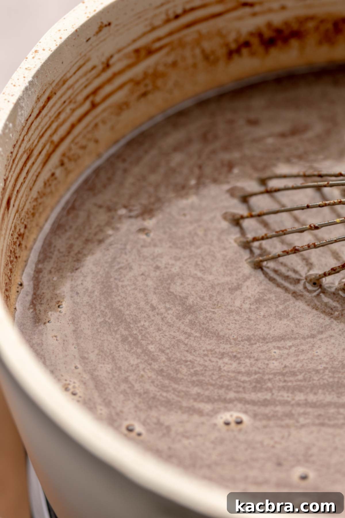 Chocolate pudding ingredients being mixed together in a pot with a whisk.