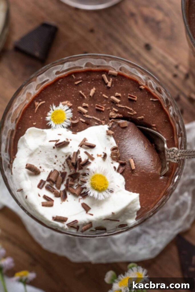 Dark chocolate pots de creme with whipped cream and a spoon in it.