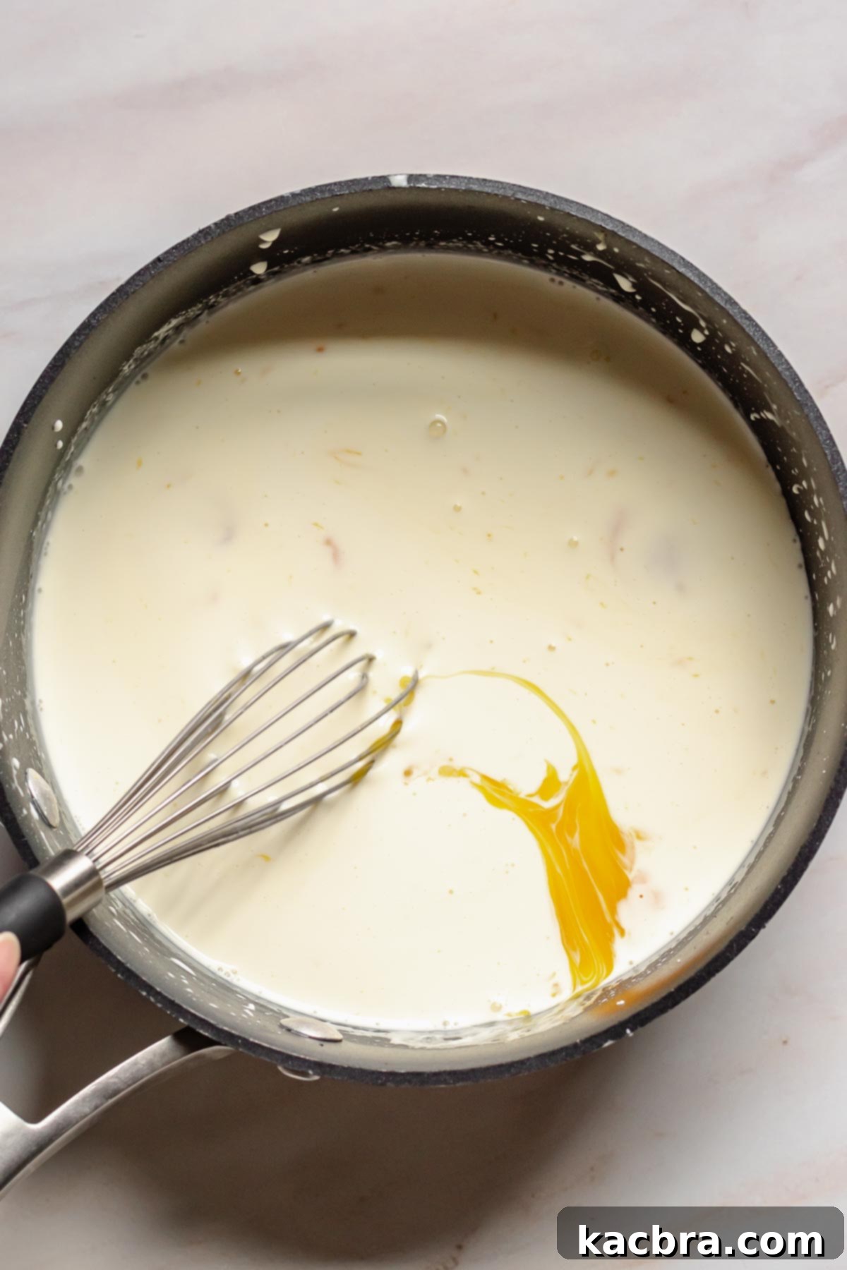 Whisking egg yolks and cream in a pot.