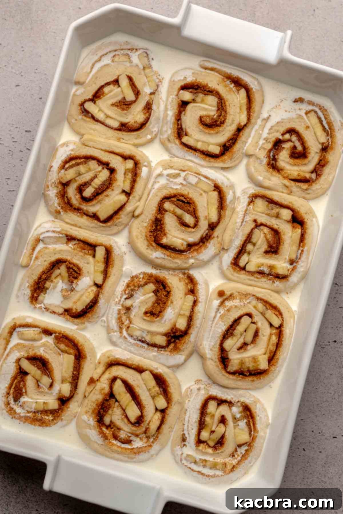 Banana cinnamon rolls generously drizzled with heavy cream in the pan, just before baking.