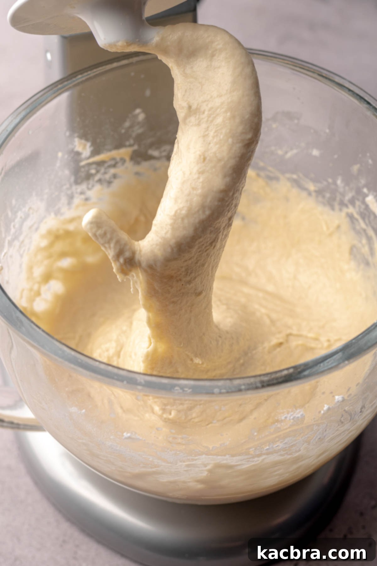 Brioche dough halfway mixed on a dough hook, showing its initial wet consistency.