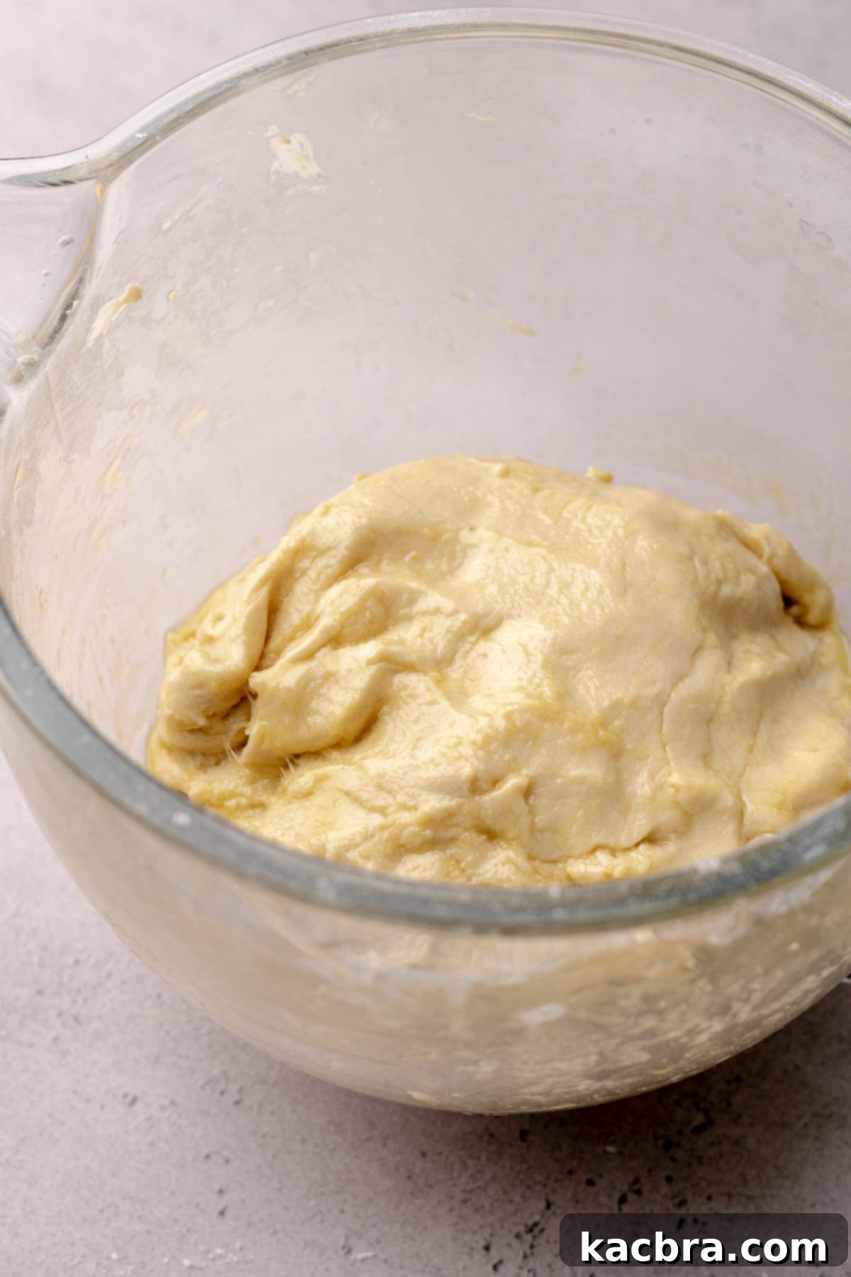 Cinnamon roll dough covered in olive oil before rising in a large mixing bowl.