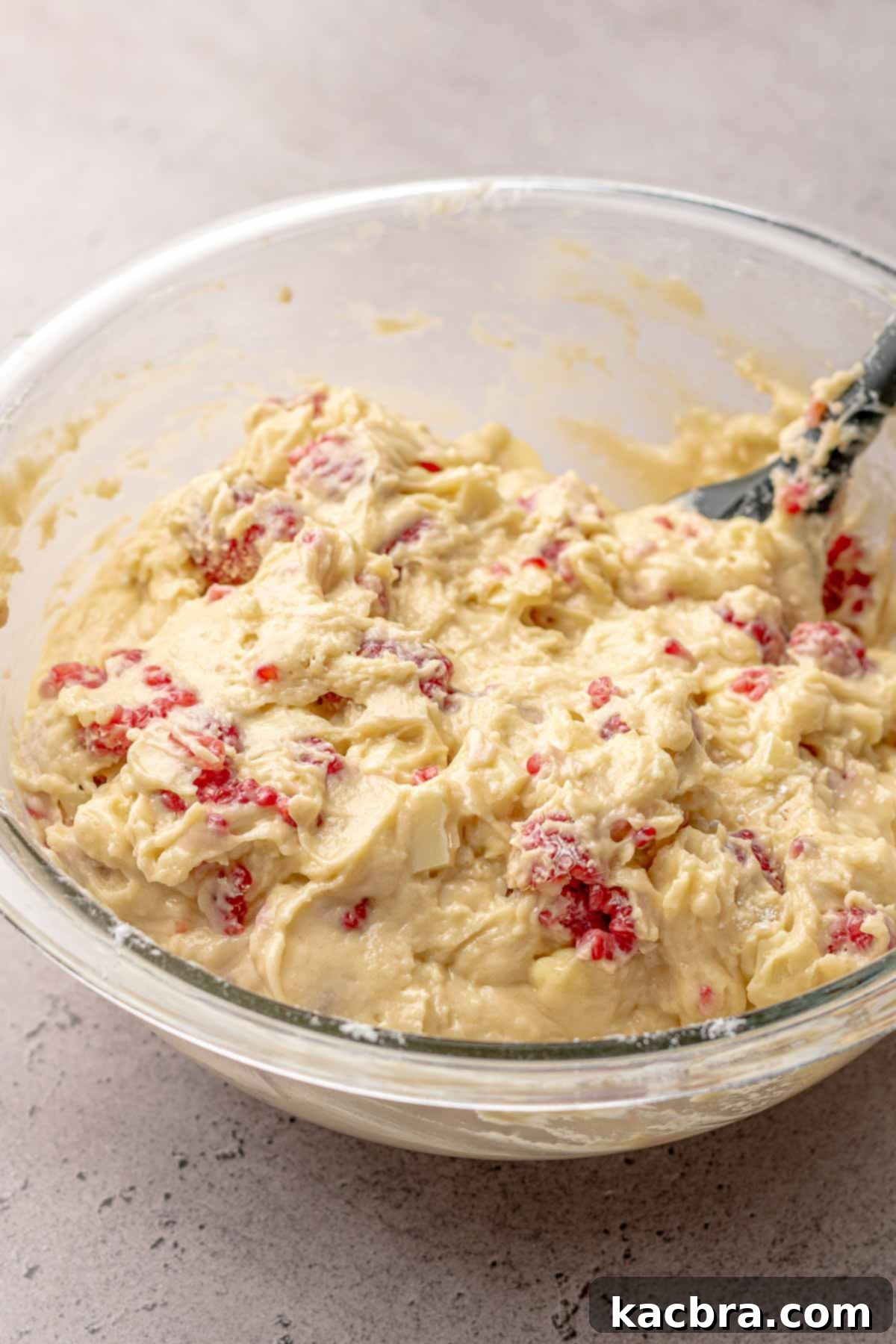 The completed white chocolate raspberry muffin batter, rich with berries and chocolate chunks, perfectly mixed and ready for baking.