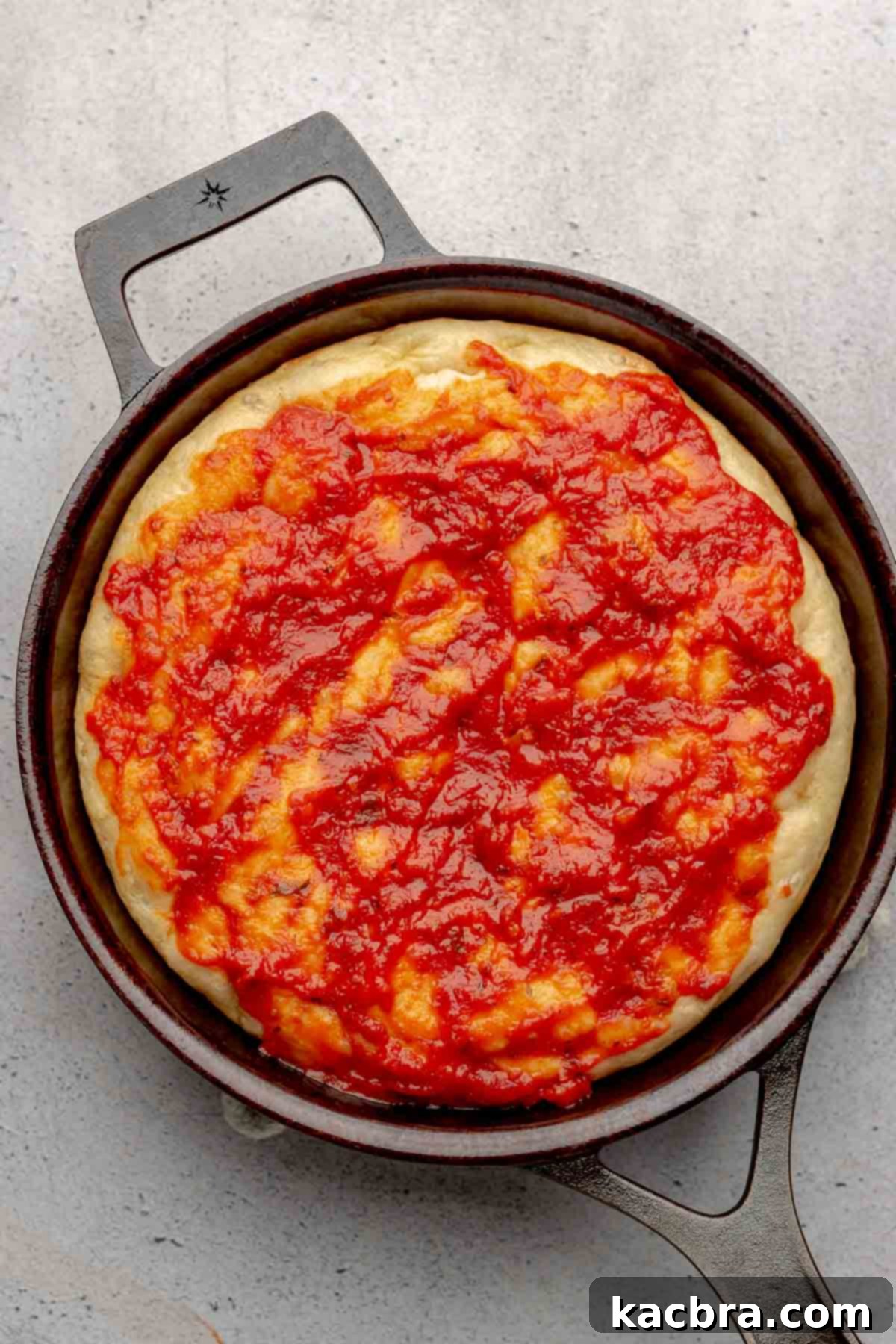 Pizza dough with sauce on top.