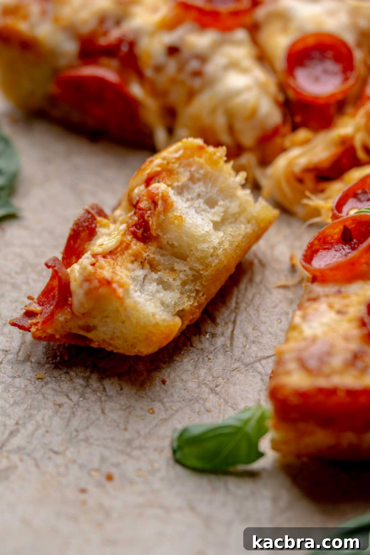 A half eaten piece of pan pizza on parchment paper.