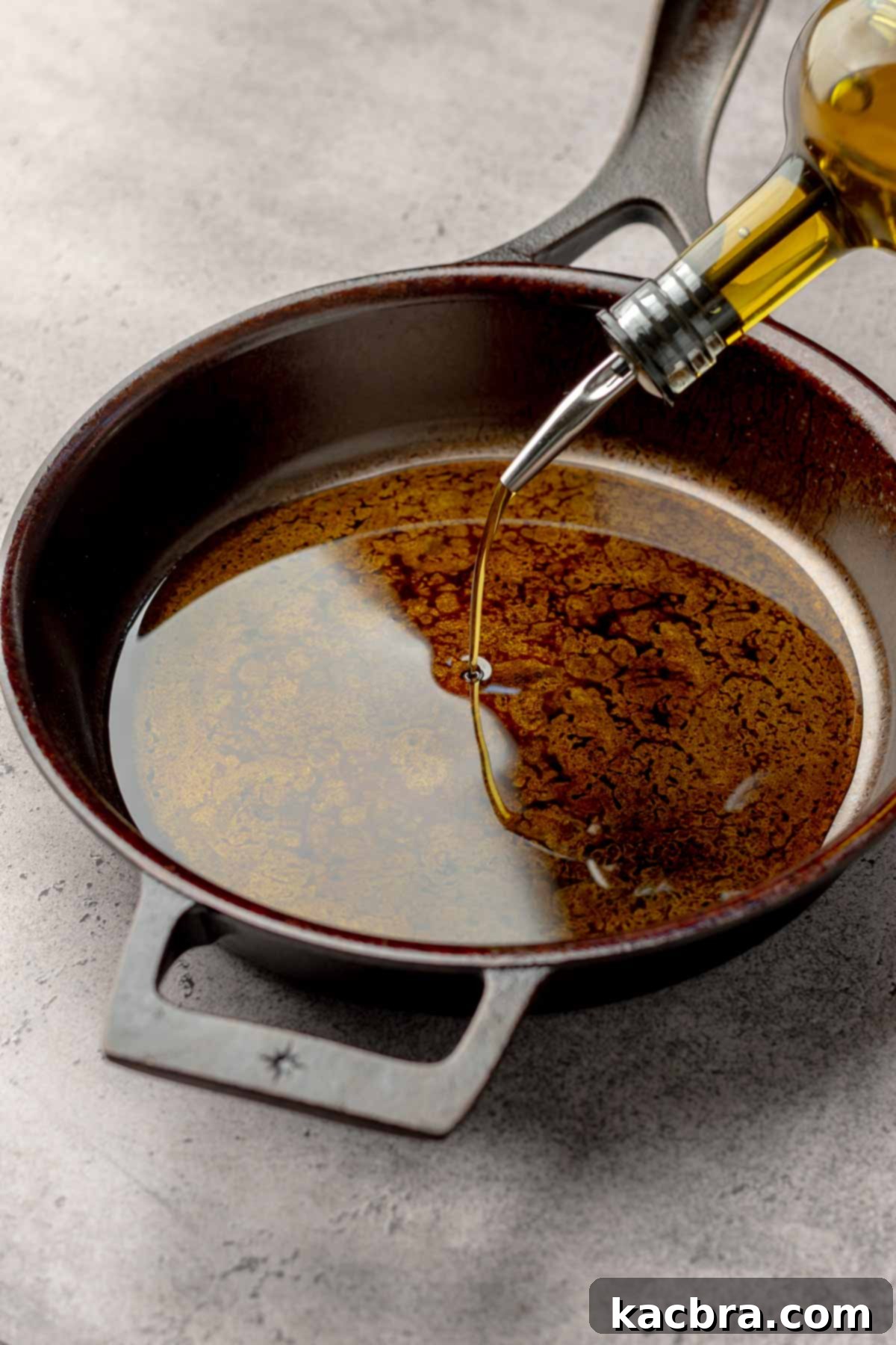 Olive oil being poured into a cast iron pan.