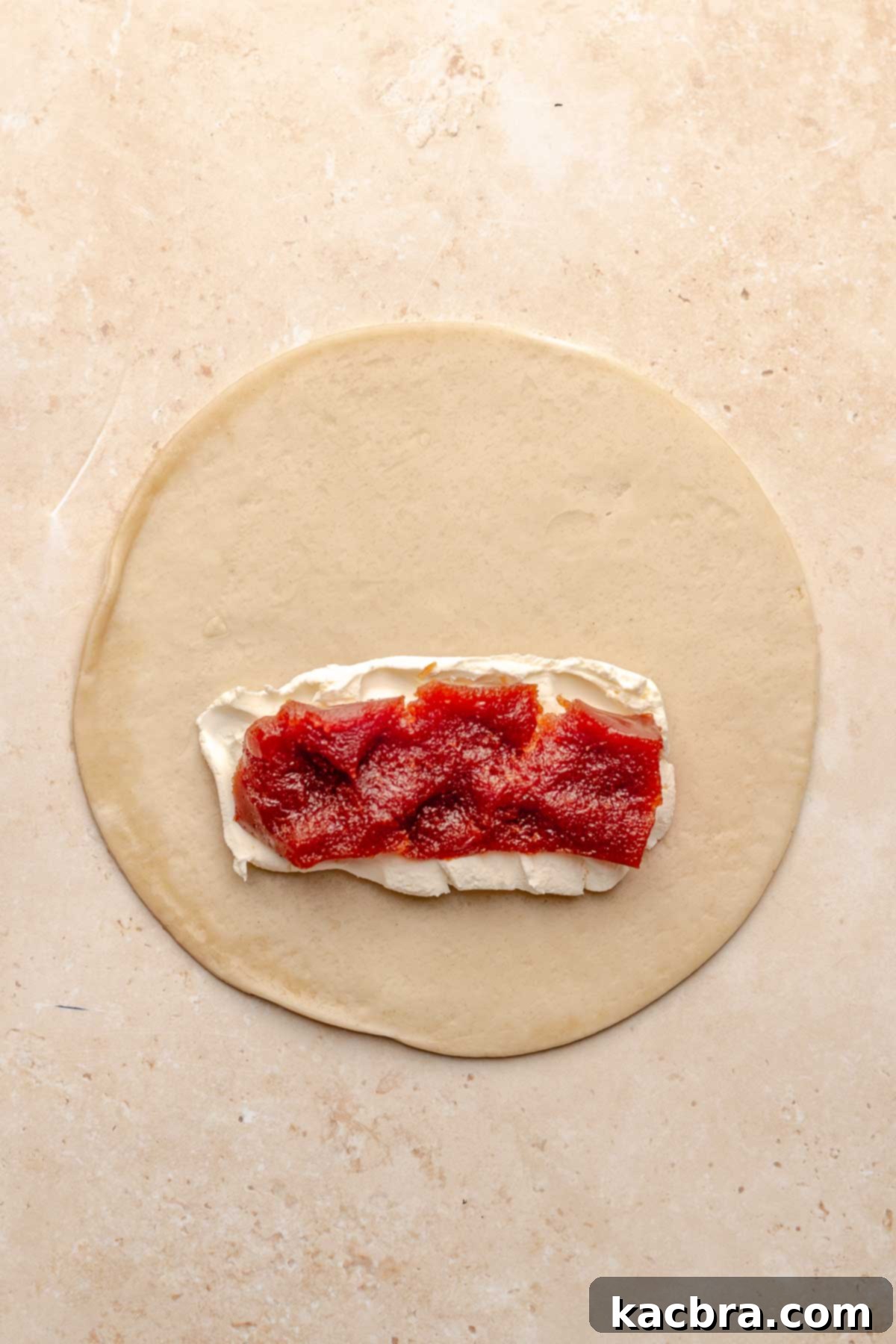 Guava paste spread on top of cream cheese on a disc of empanada.