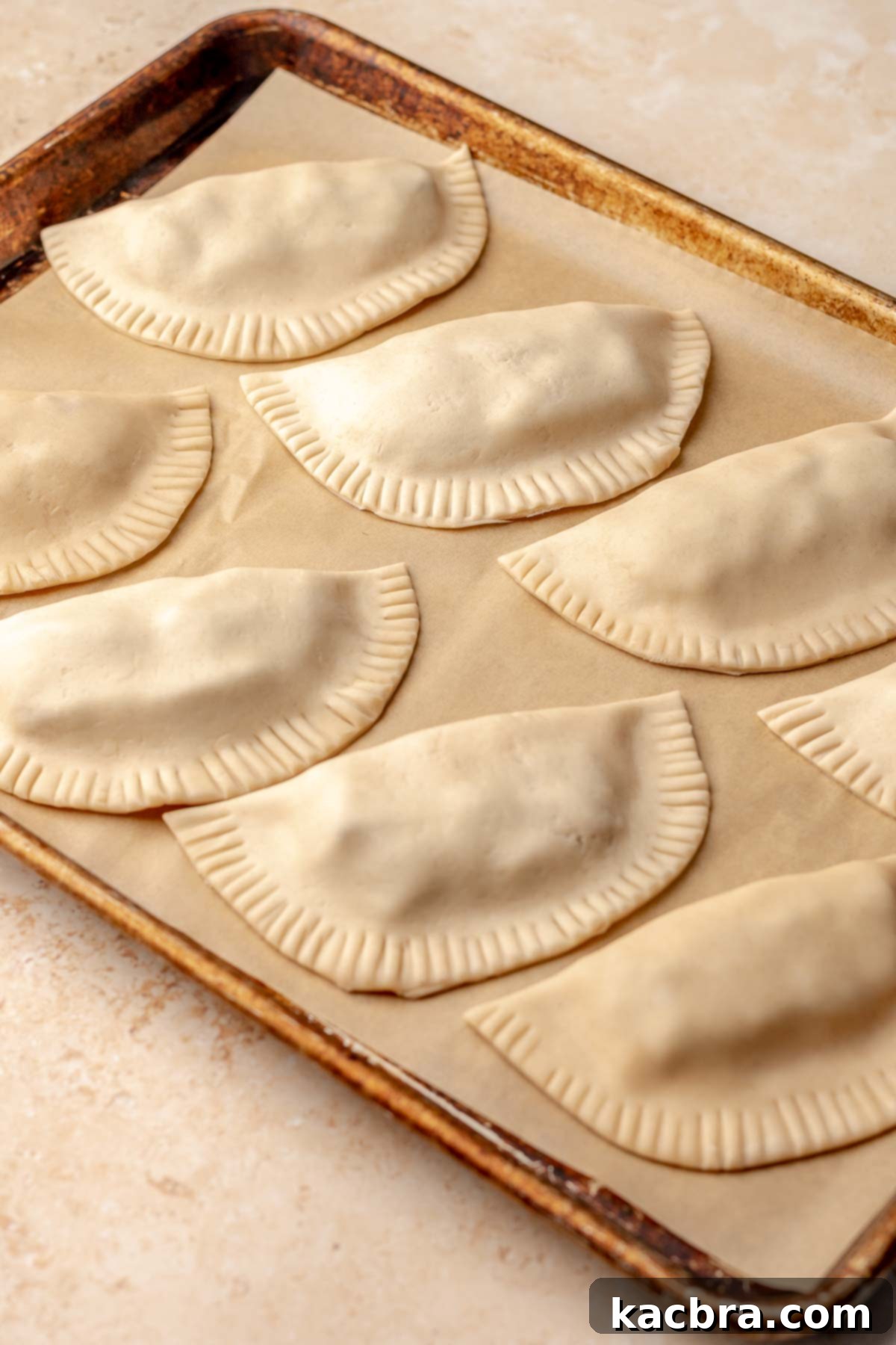 Crimped empanadas on a sheet pan.