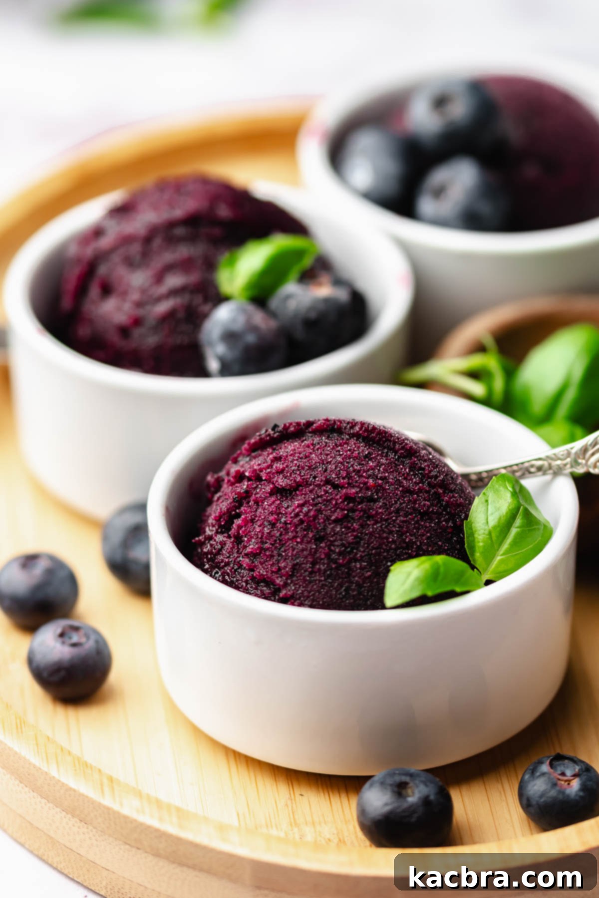 Blueberry sorbet in a cup with basil leaves.