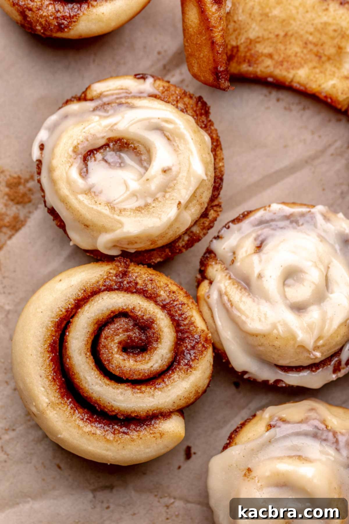 An array of mini cinnamon rolls, half are frosted.