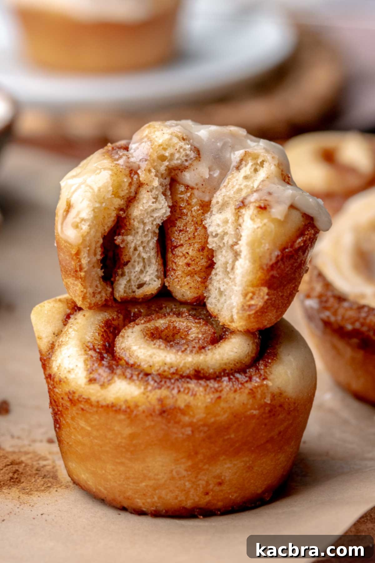 A stack of two mini cinnamon rolls. The top has a bite removed.