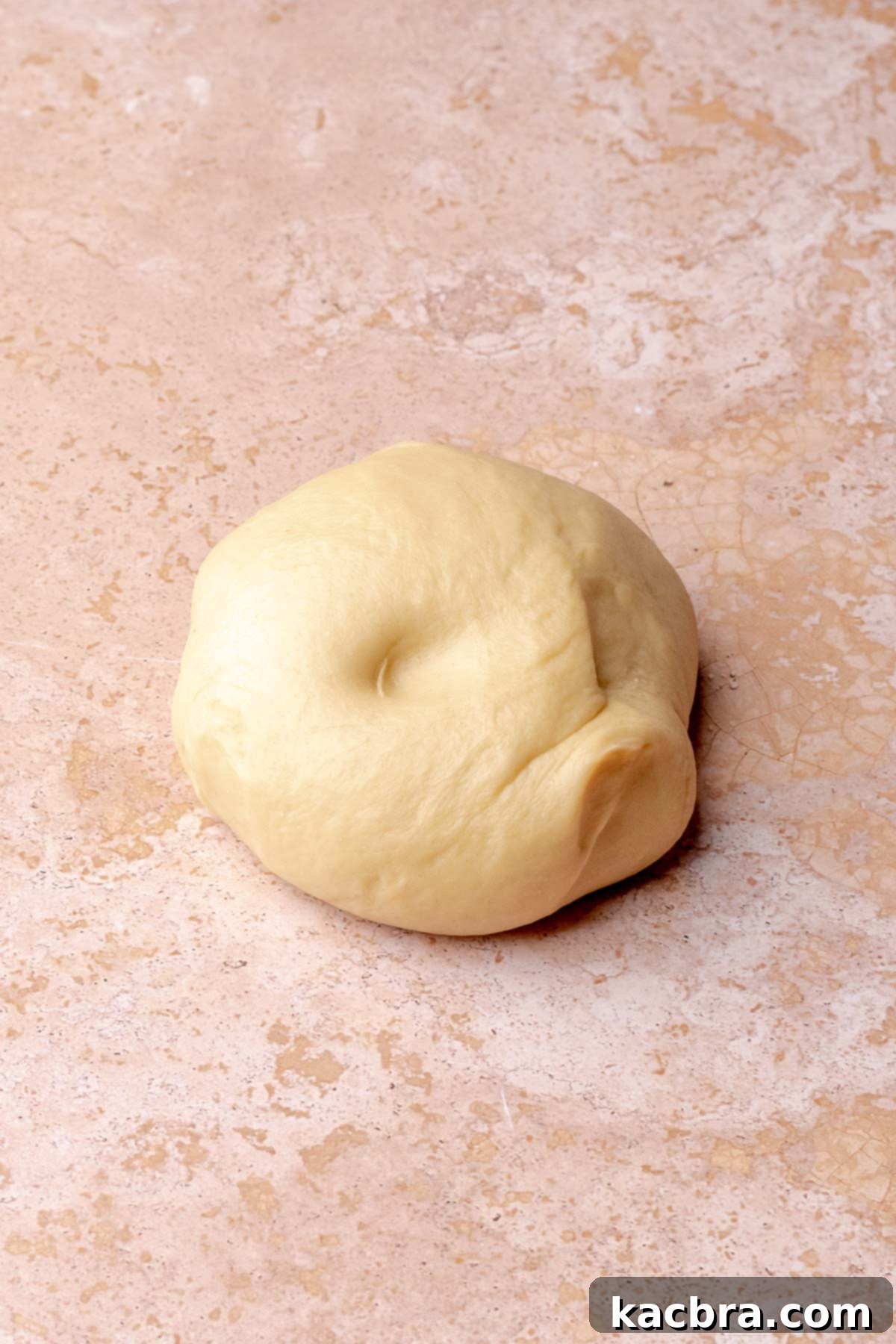 A ball of kneaded cinnamon roll dough on a counter.