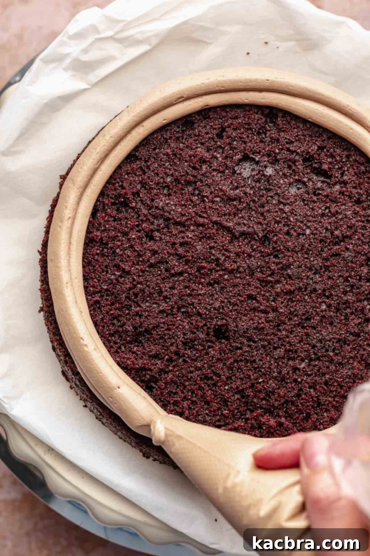 A piping bag pipes a frosting dam around the outside of the cake.