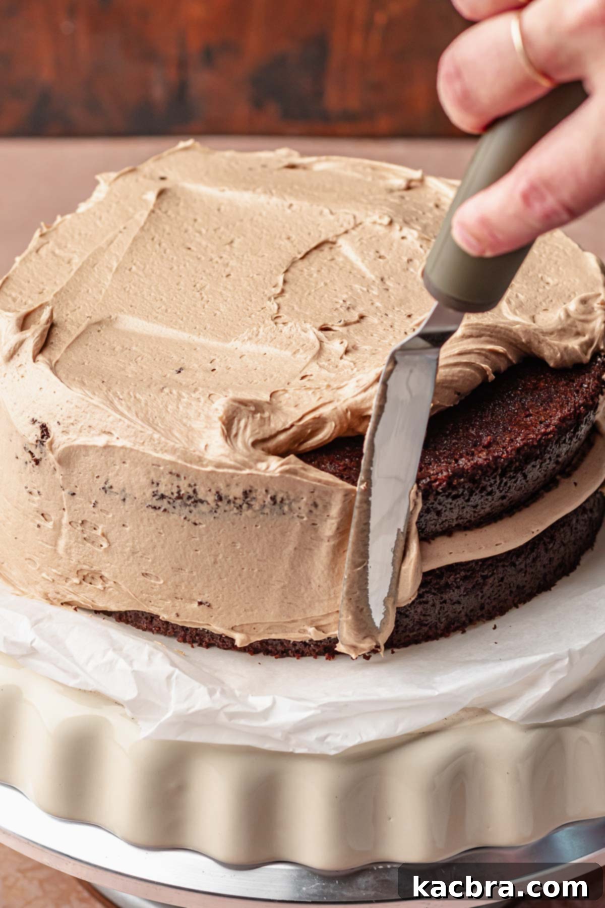 A spatula smooths nutella buttercream onto the chocolate hazelnut cake.