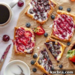 Various fruit and cheese danishes on a table with coffee nearby.