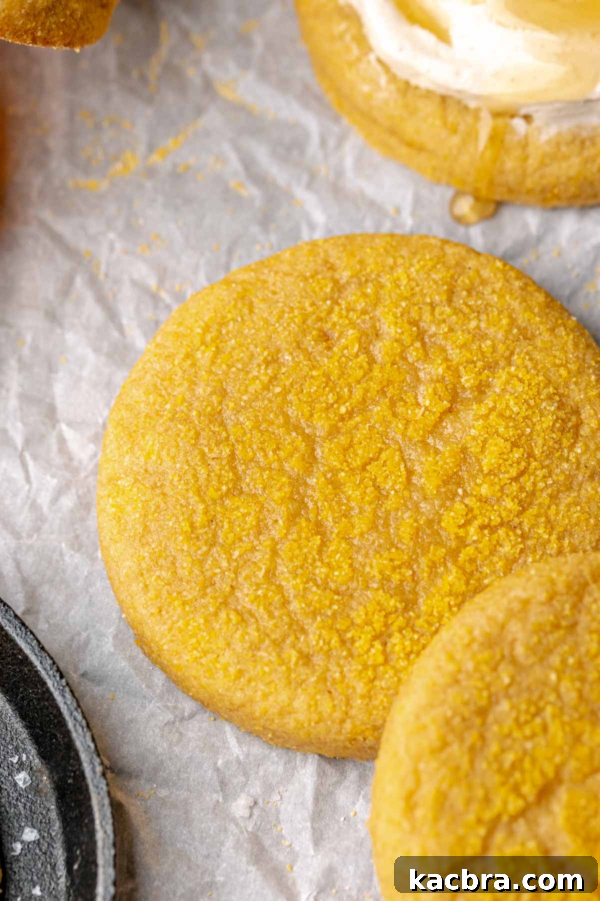 Warm Cornbread Cookies with Whipped Honey Butter 12 An unfrosted cornbread cookie on parchment paper, displaying its golden hue and texture.