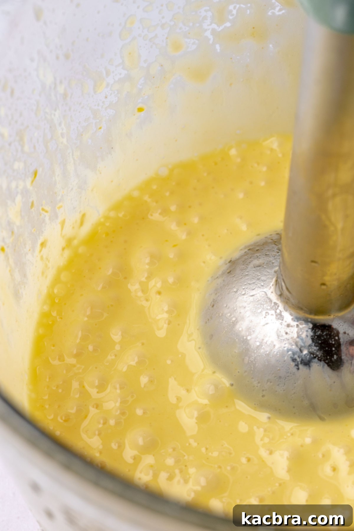 Fluffy Savory Rolls with Golden Hollandaise 15 A blender emulsifying hollandaise sauce in a tall measuring cup.