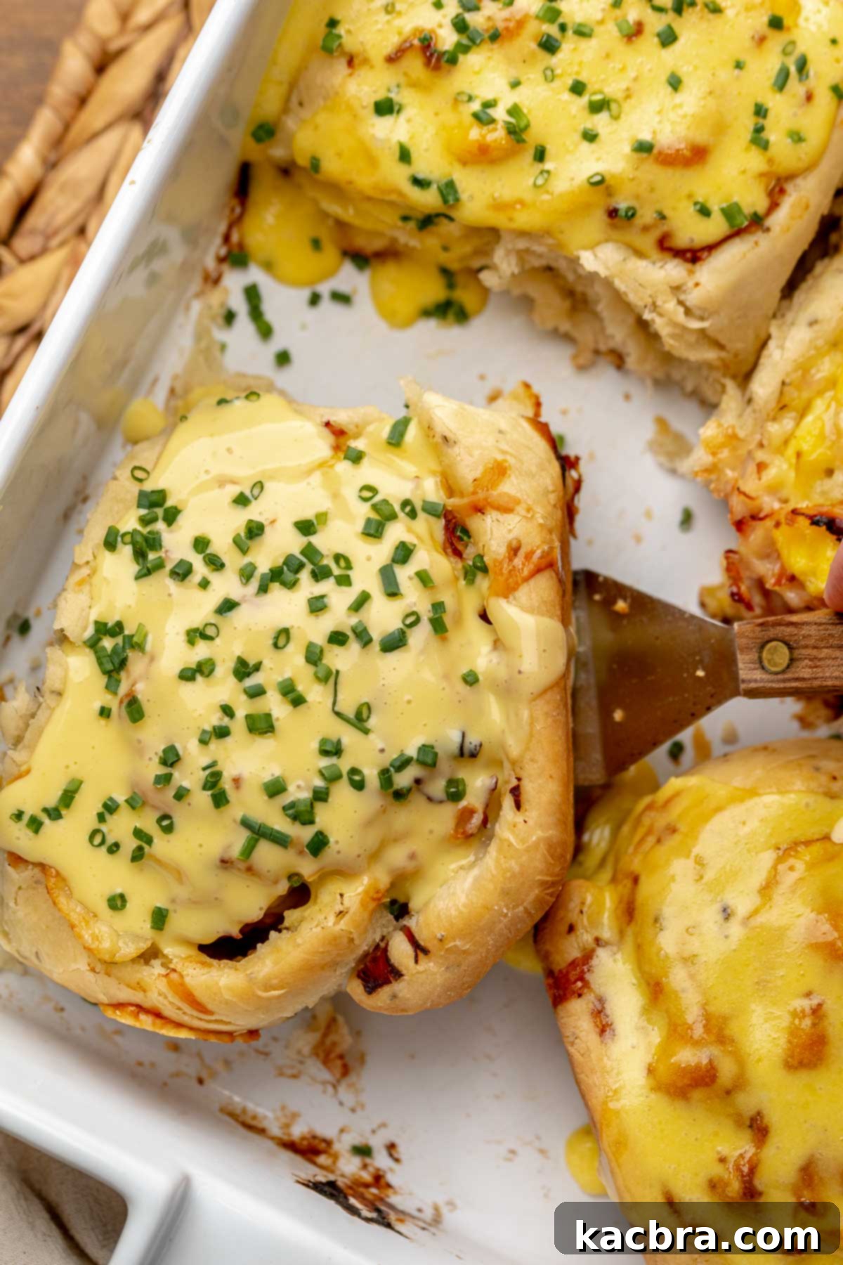 Fluffy Savory Rolls with Golden Hollandaise 17 Savory cinnamon roll topped with hollandaise sauce and fresh chives in a casserole dish, ready to be served.