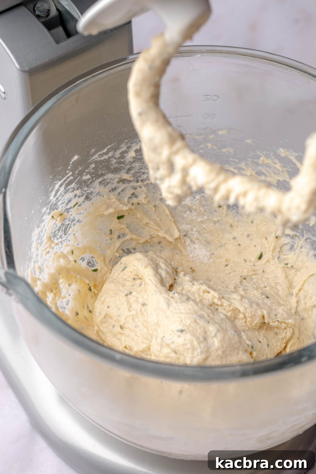 Fluffy Savory Rolls with Golden Hollandaise 7 Herbed cinnamon roll dough in a bowl with a dough hook during kneading.