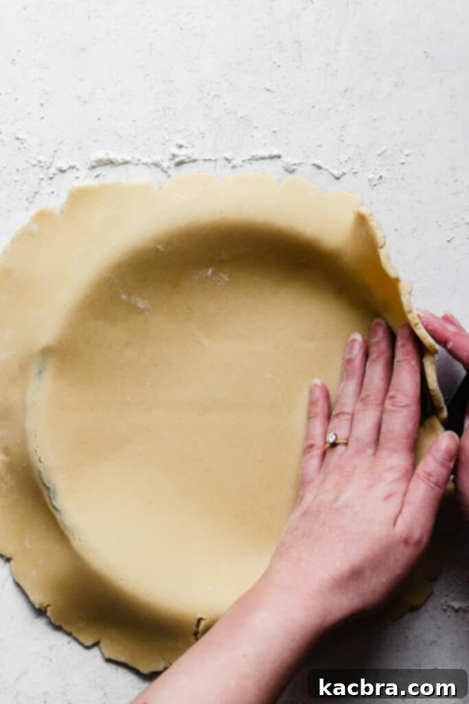 Folding excess dough inwards over the tart pan edge to reinforce the sides of the crust.