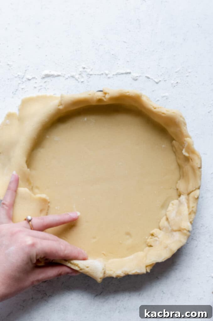 Trimming excess dough from the tart pan with a rolling pin for a clean edge.