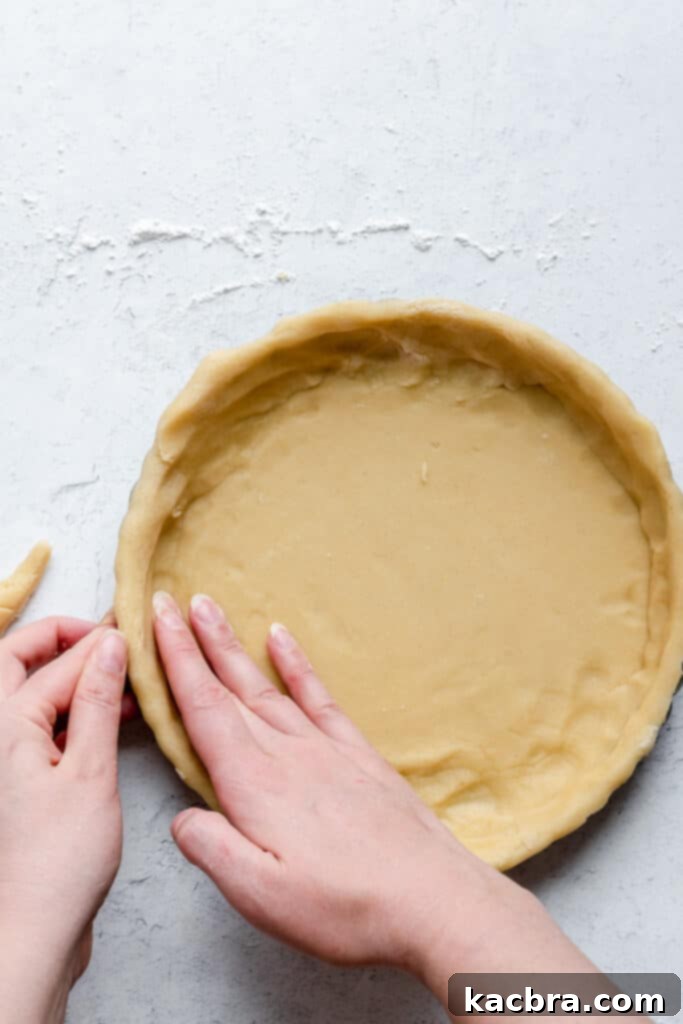 Pressing dough into tart pan sides for a smooth, even finish.