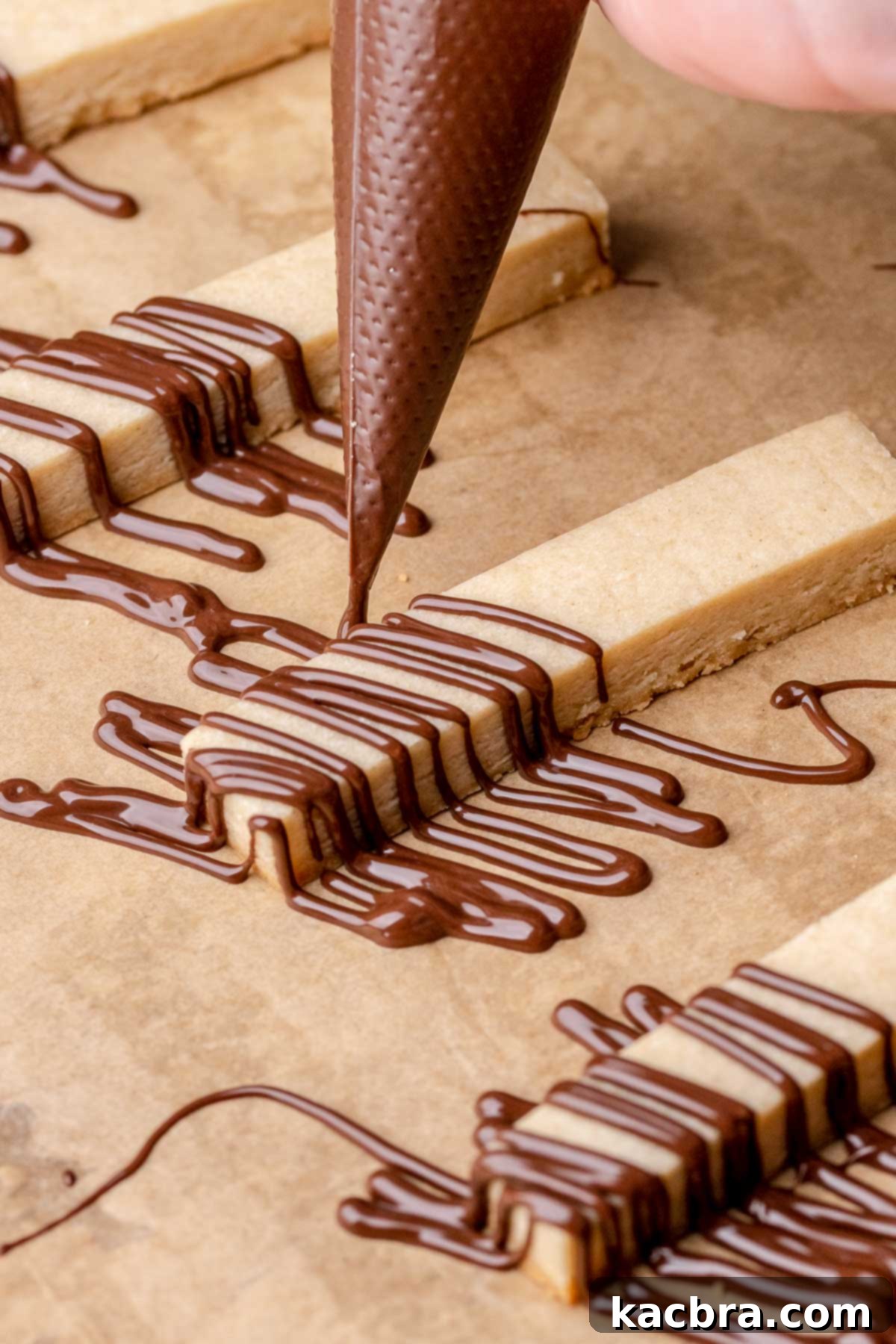 Irresistible Chocolate Cookie Dippers 18 A piping bag elegantly drizzles melted chocolate onto a baked cookie stick for decoration.