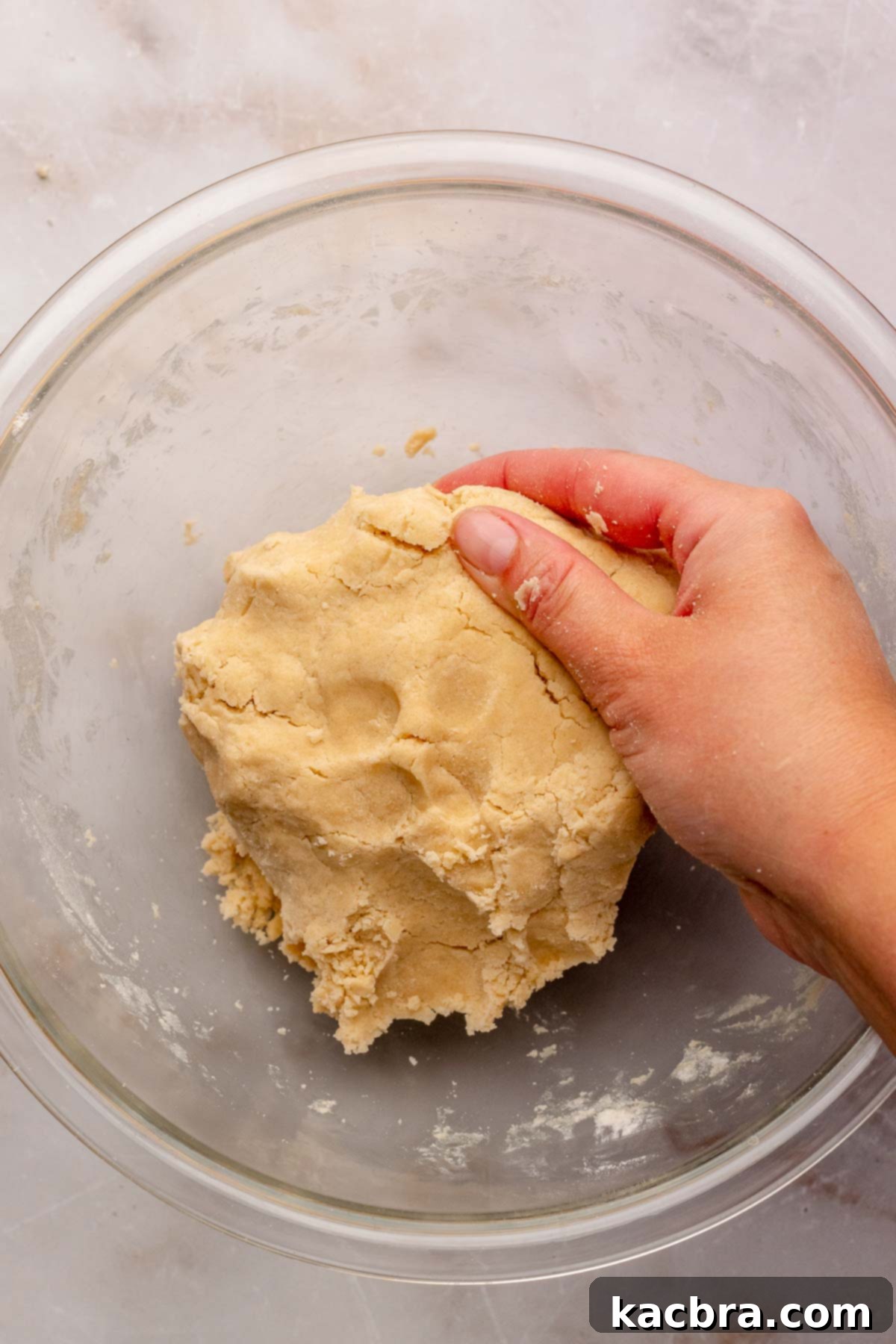 Irresistible Chocolate Cookie Dippers 8 A hand gently presses together shortbread dough in a bowl to form a cohesive mass.