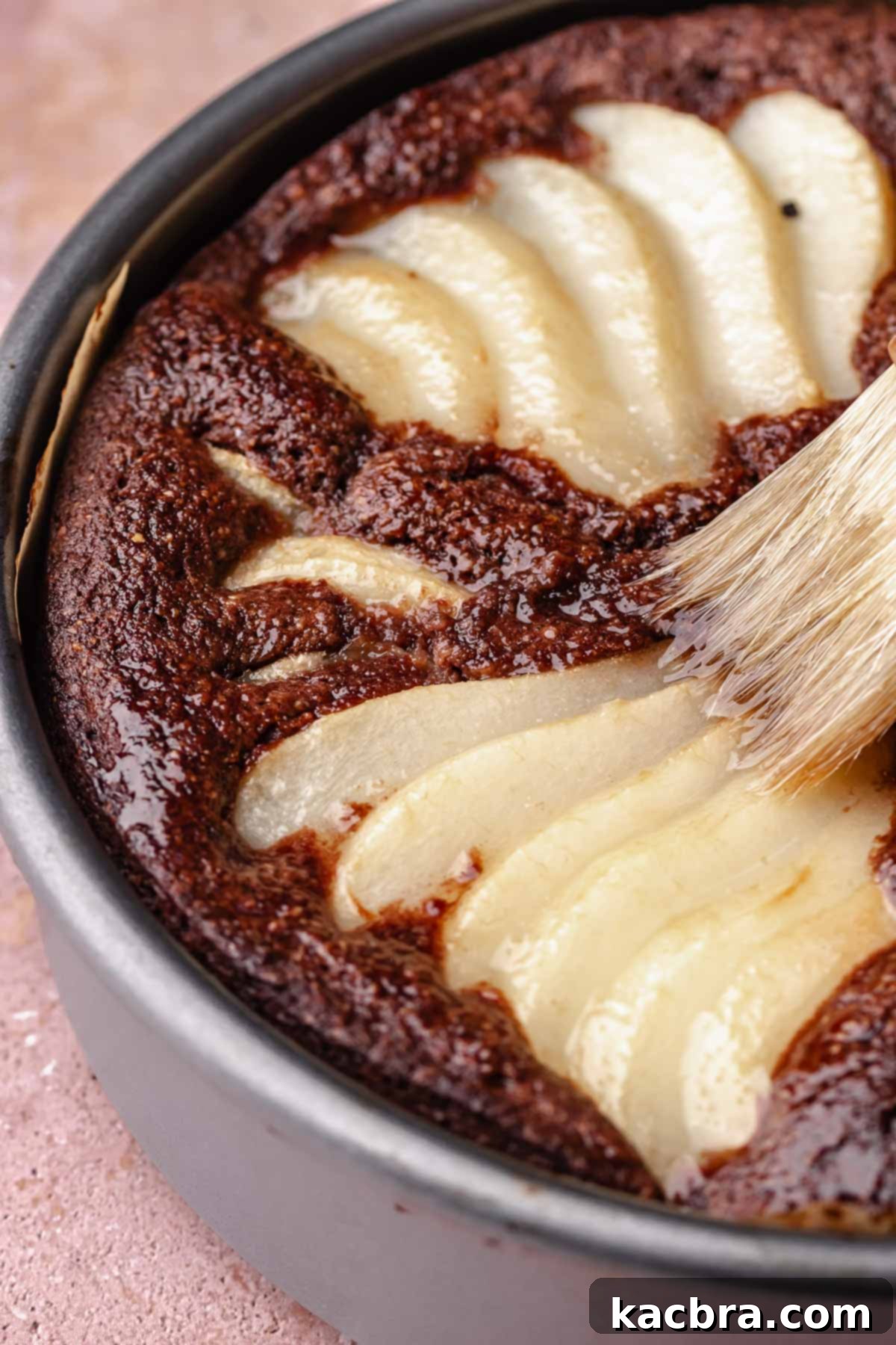 Pear-Kissed Chocolate Cake 11 A pastry brush brushes simple syrup on top of the baked chocolate pear cake.