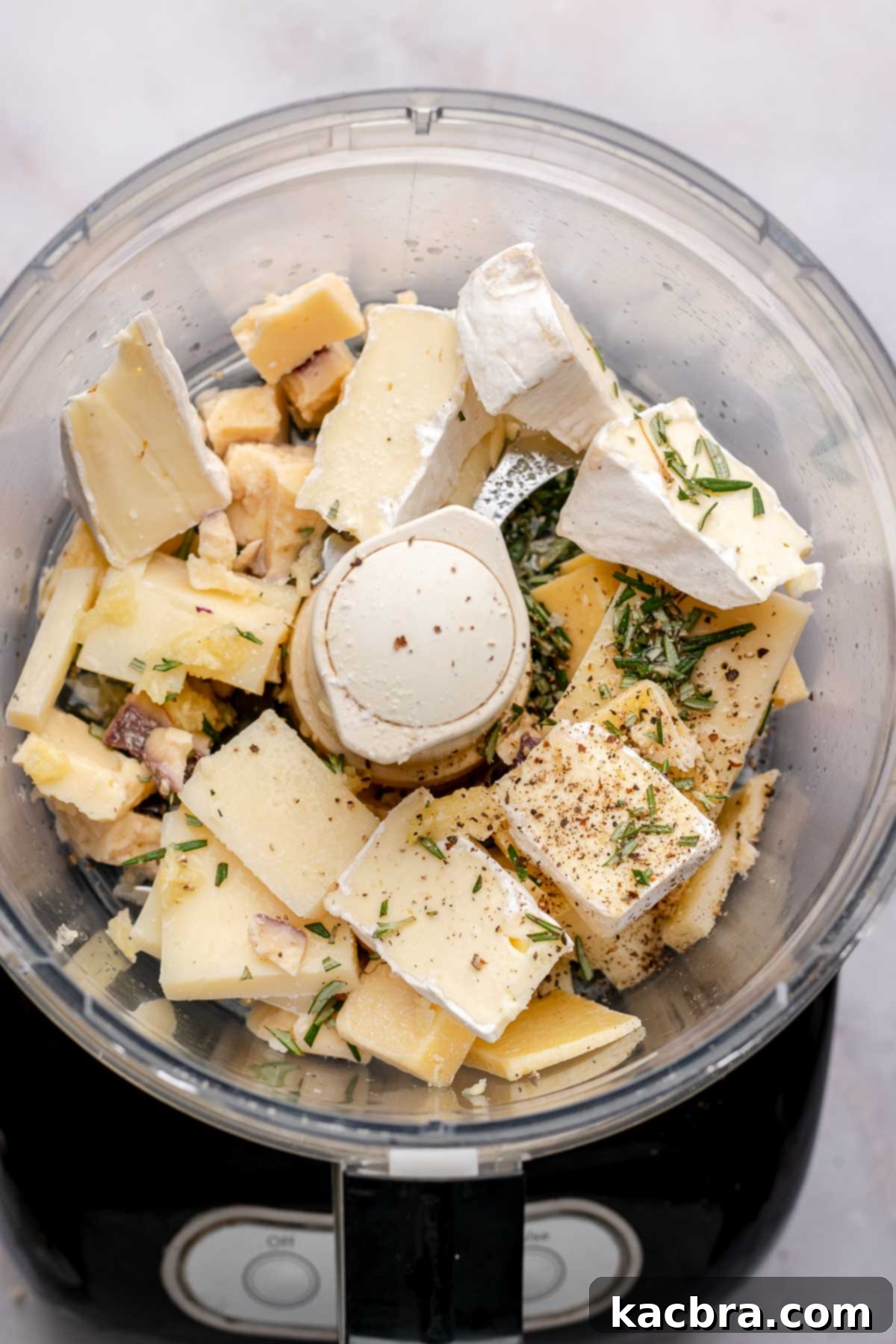 Intense Cheese Revival 4 Pieces of cheese and herbs in the bowl of a food processor.