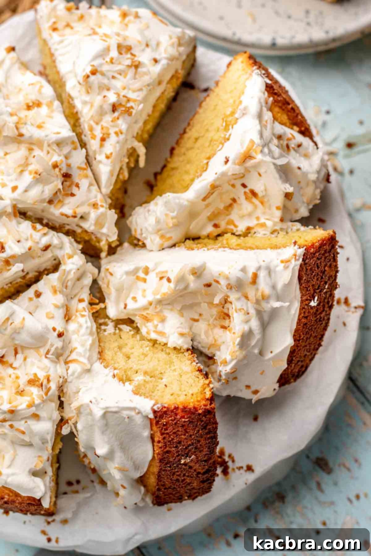 A whole coconut almond cake, freshly sliced, on a platter.