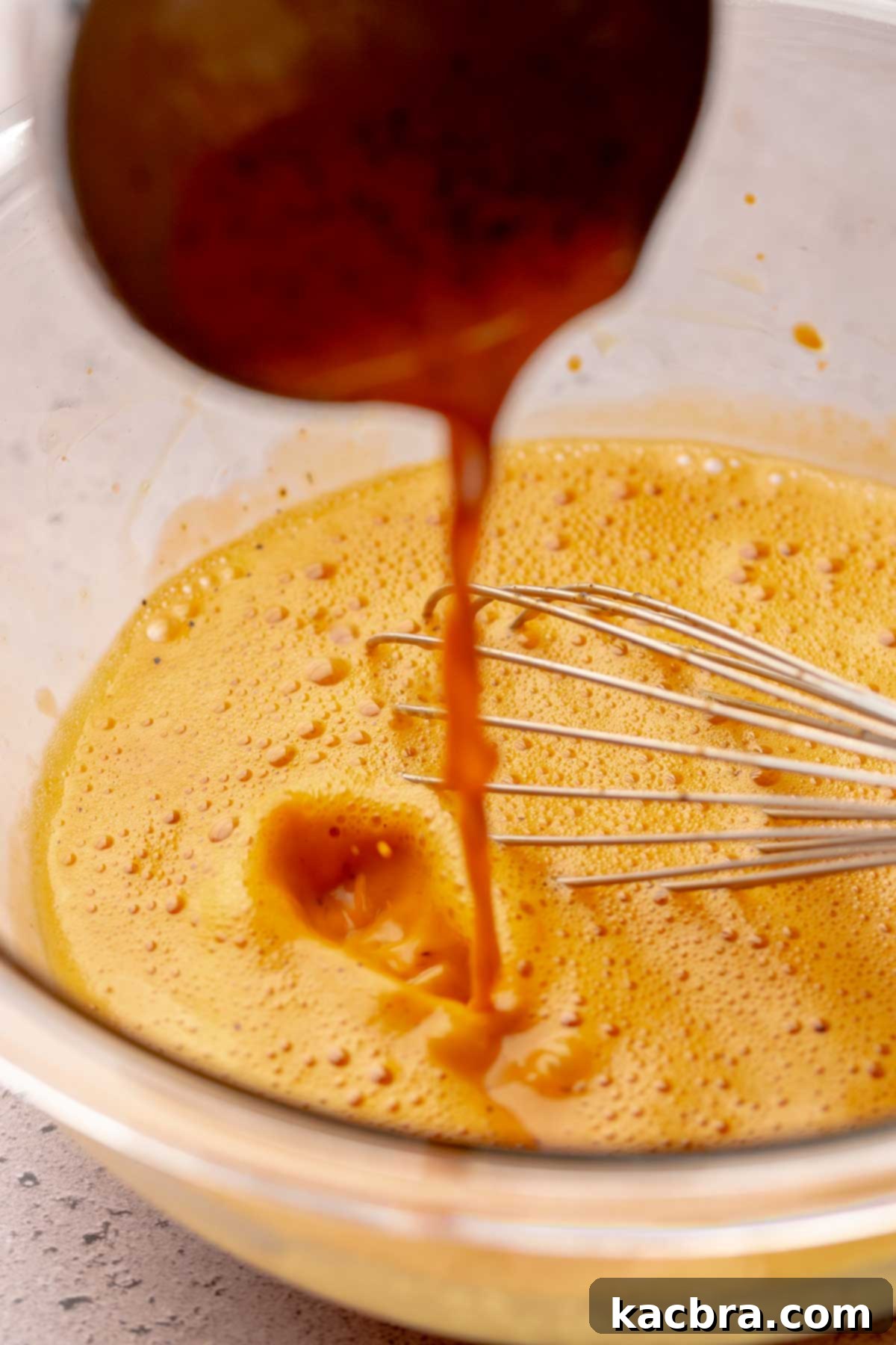 Thai tea drizzles into egg yolks in a bowl.