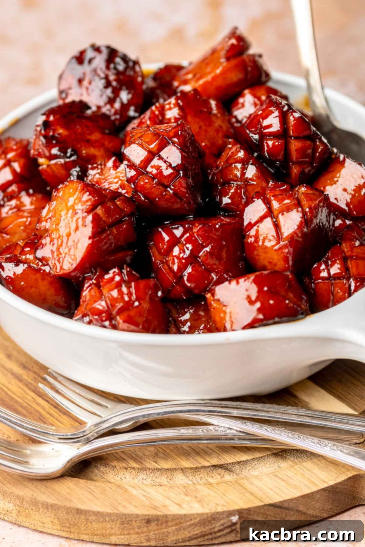 A bowl full of kielbasa bites with cocktail forks next to it.