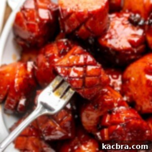 A fork holds a chunk of kielbasa in a bowl of other pieces.