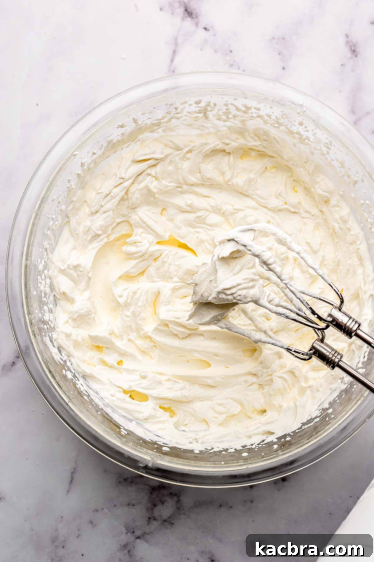Beaters whipping heavy cream in a bowl.