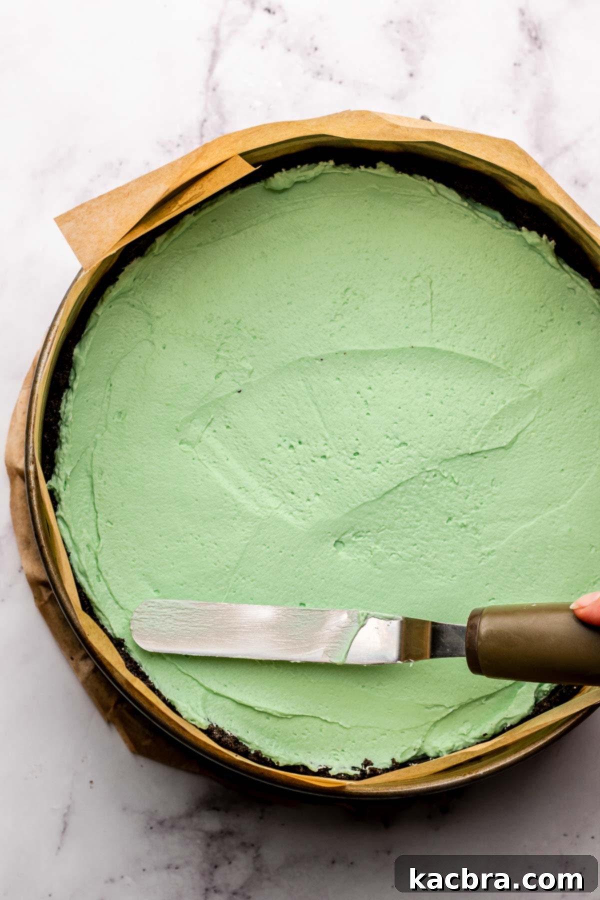 An offset spatula spreads mint pie filling into the pie.
