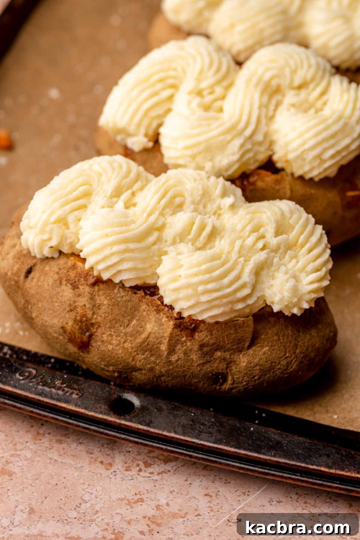 Piped mashed potatoes on top of baked potatoes.