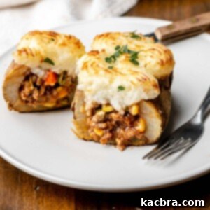Stuffed potato cut open on a plate with a fork on it.