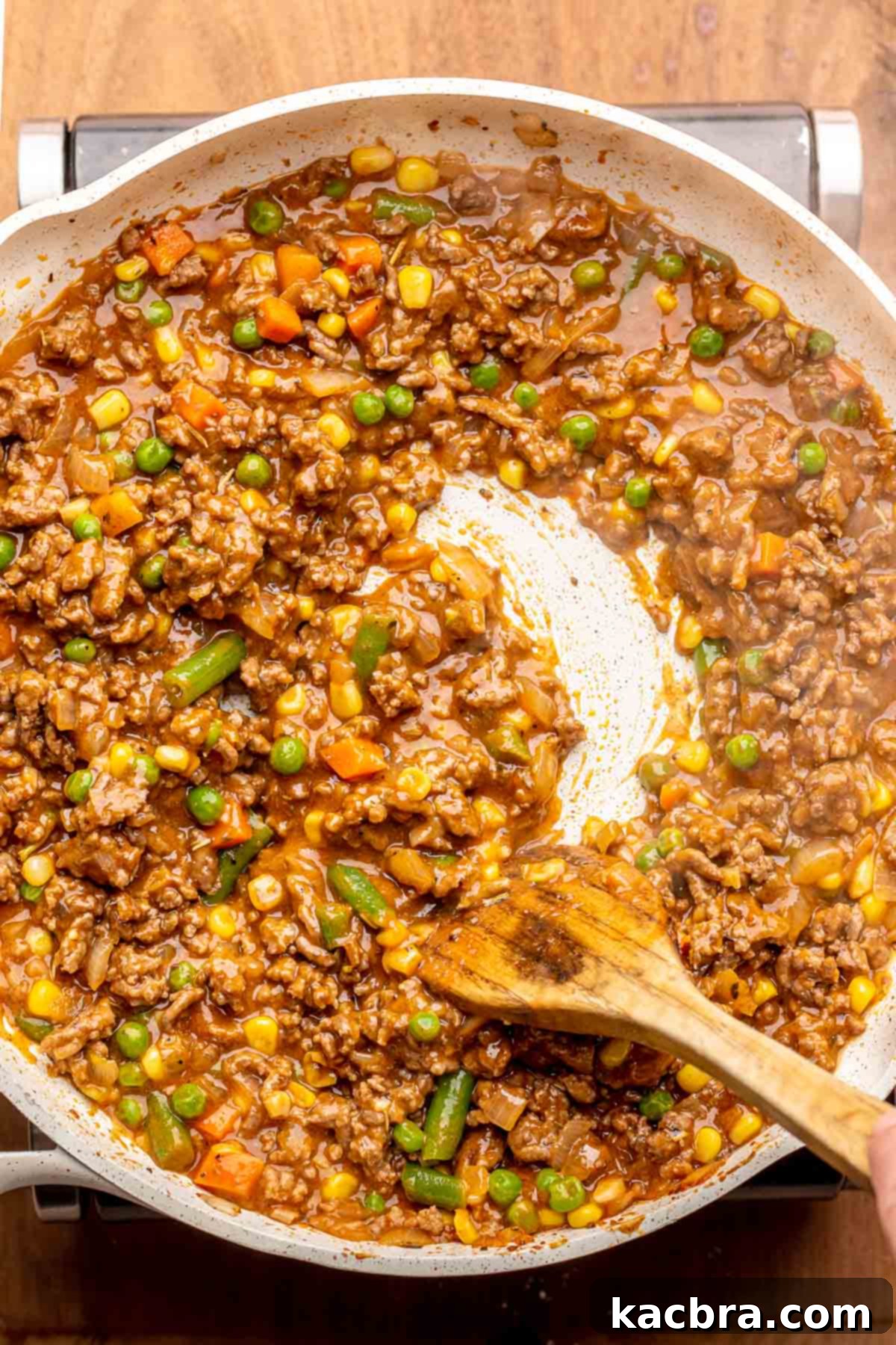 A spoon stirs shepard's pie filling in a pan.