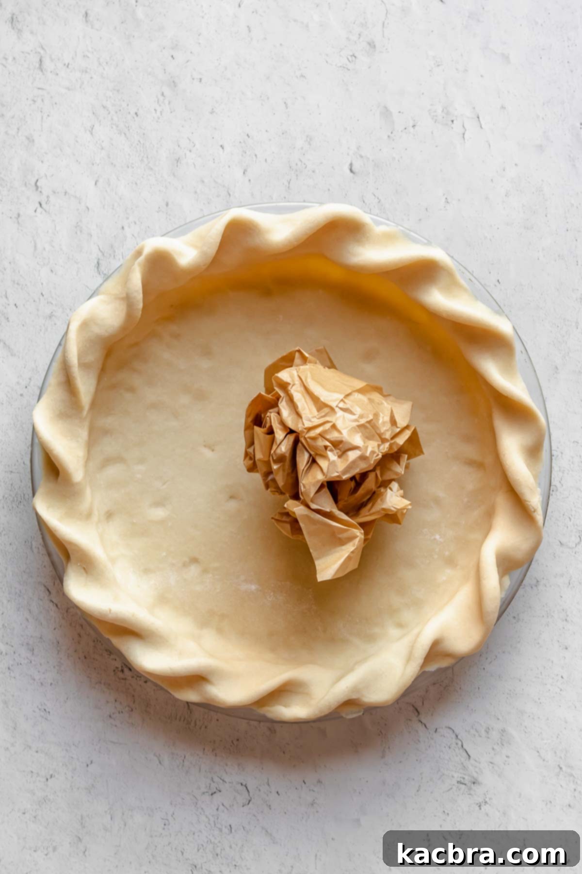 Perfectly Flaky All-Butter Crust 15 Tightly crumbled parchment paper ready to be placed in a pie crust.