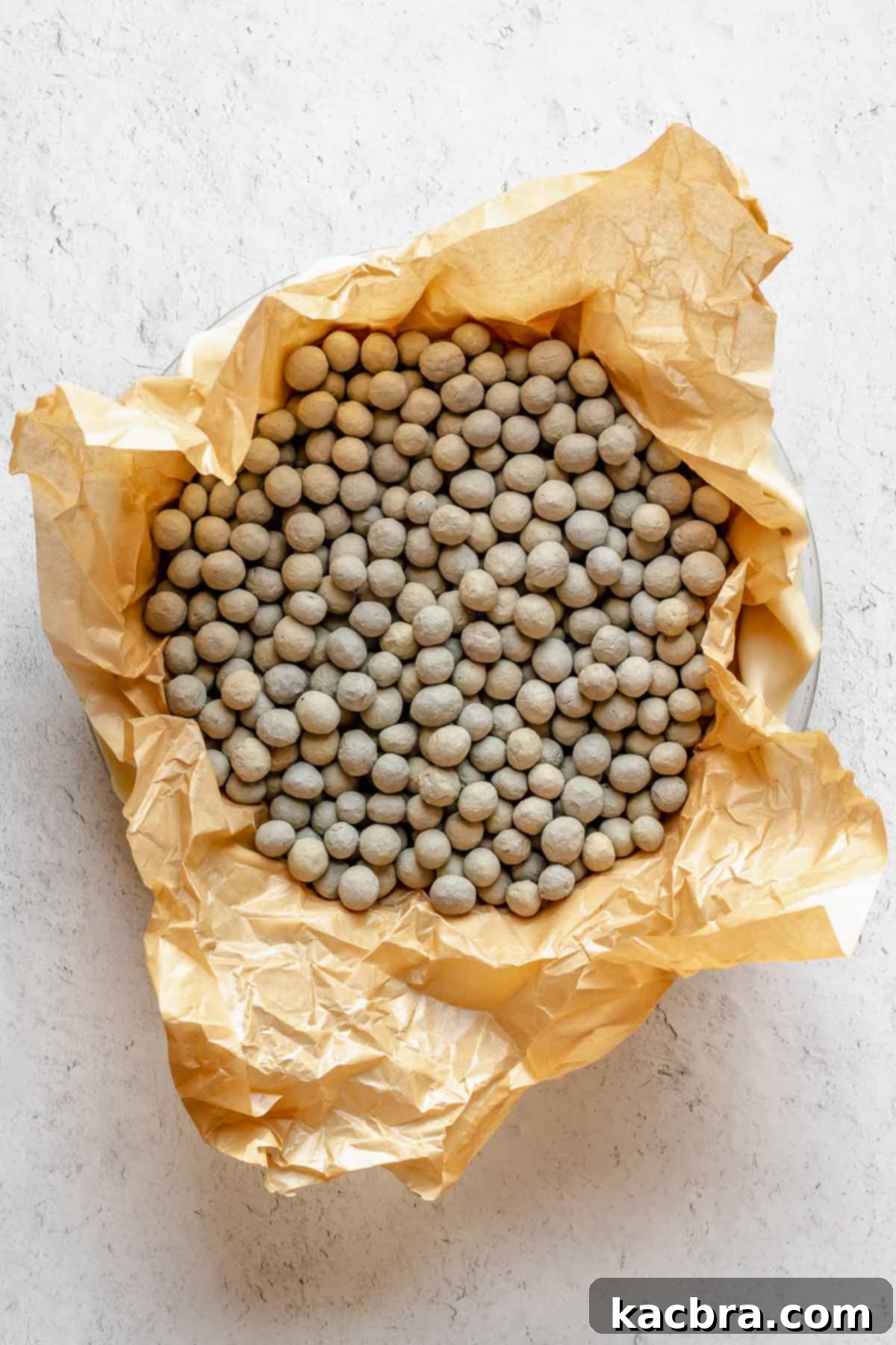 Perfectly Flaky All-Butter Crust 17 Pie weights filling a pie crust lined with parchment paper.