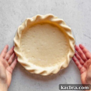 Hands hold a crimped pie crust.